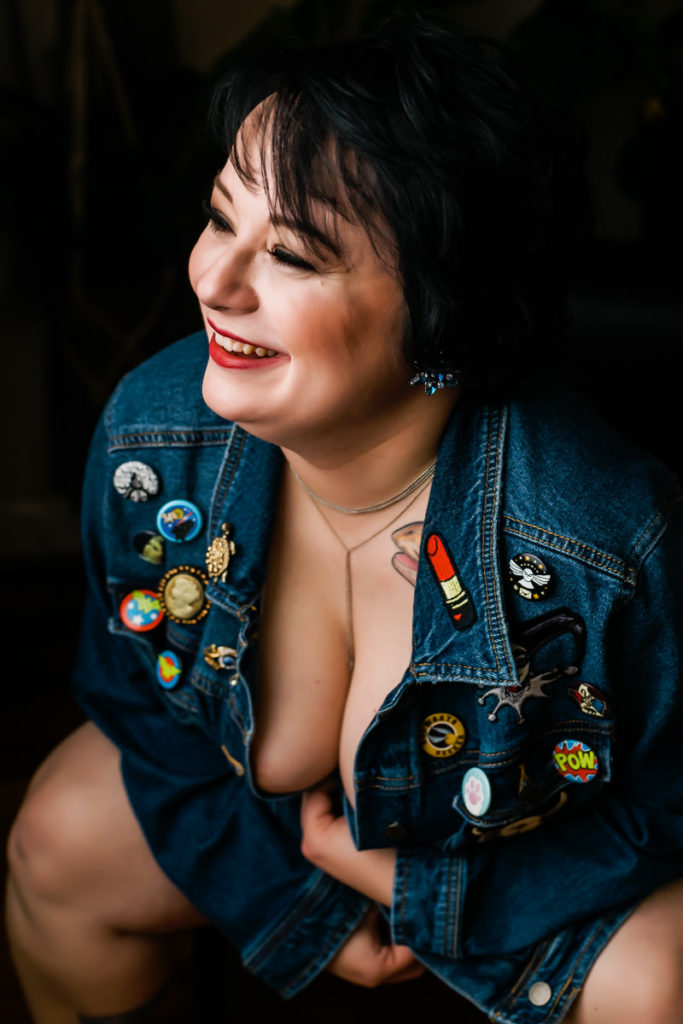 Smiling boudoir portrait of a woman wearing a denim jacket