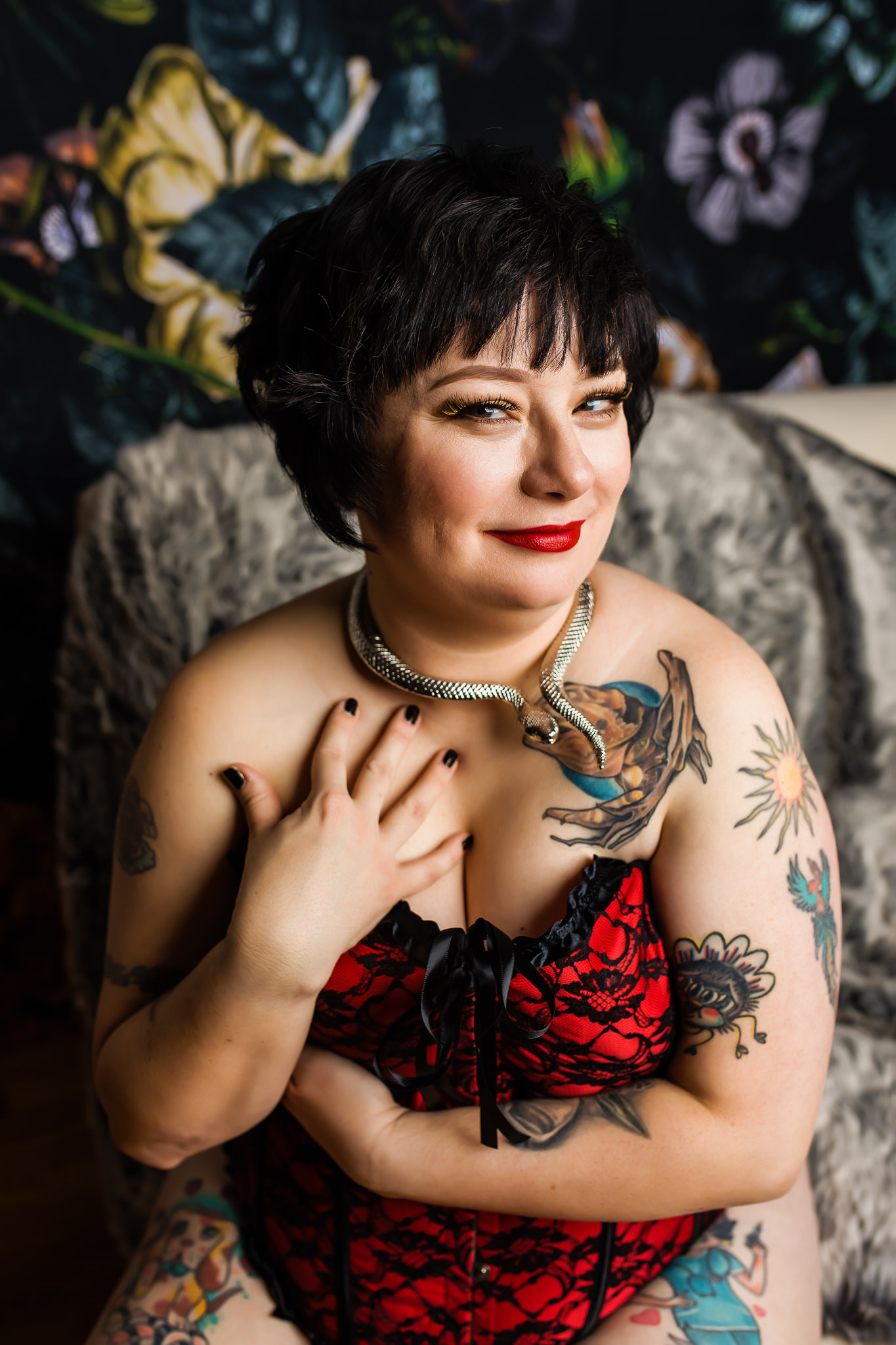 Sassy boudoir photo of a tattooed woman in a red corset